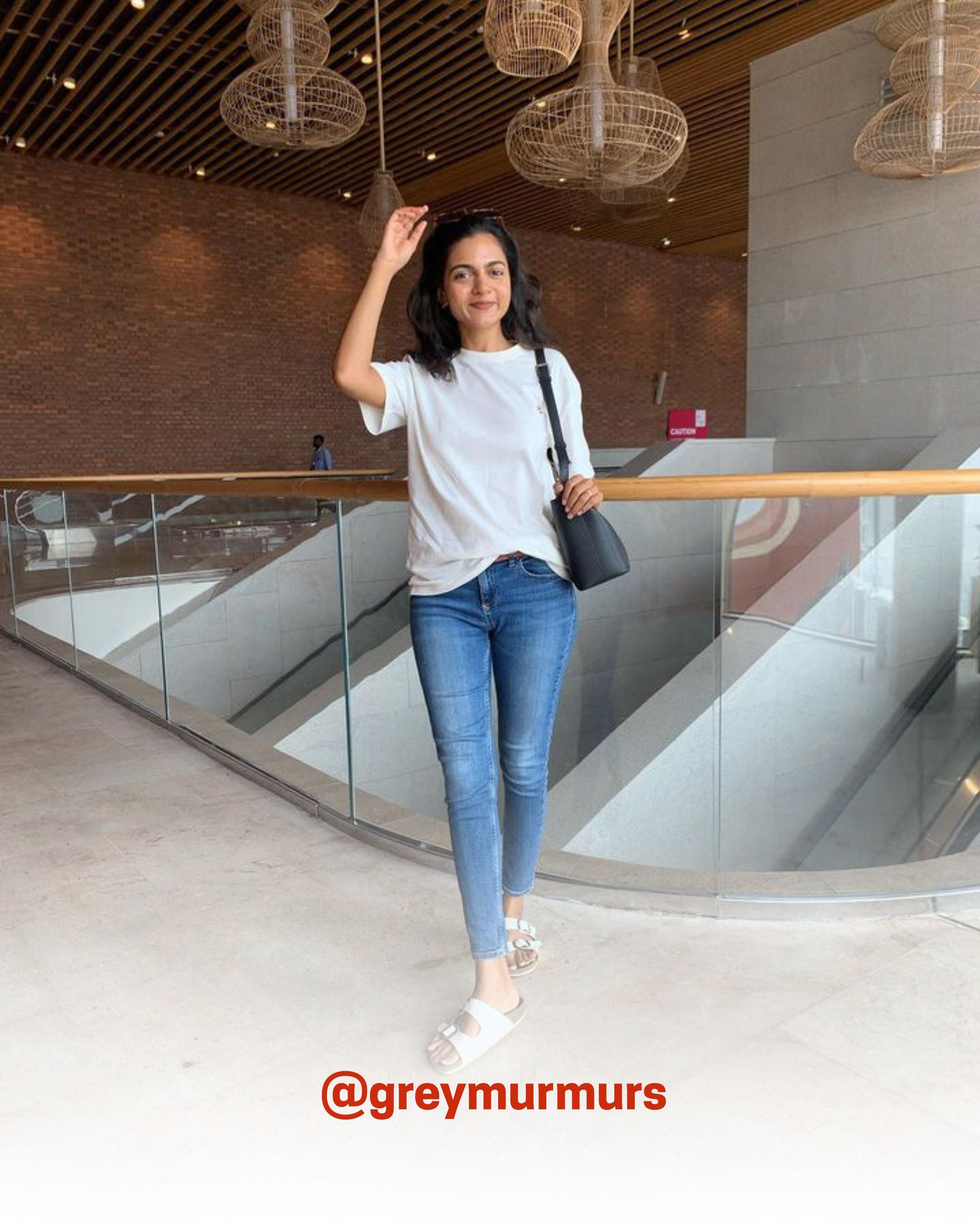 Smiling woman wearing a white organic cotton T-Shirt with blue jeans indoors, showcasing 2512’s sustainable t-shirts, a creator favorite eco friendly tee.