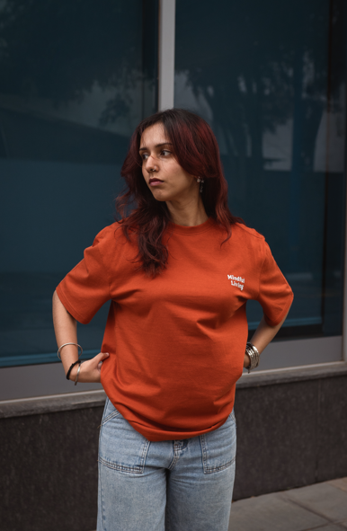 Woman wearing 2512 Pacchis Barah organic cotton t-shirt in rust orange, a unisex sustainable t-shirt designed for comfort, mindful living, and eco friendly style.