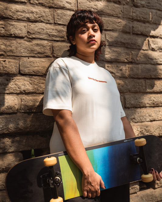 Model wearing white organic cotton unisex t-shirt with 'Live in the Moment' embroidery