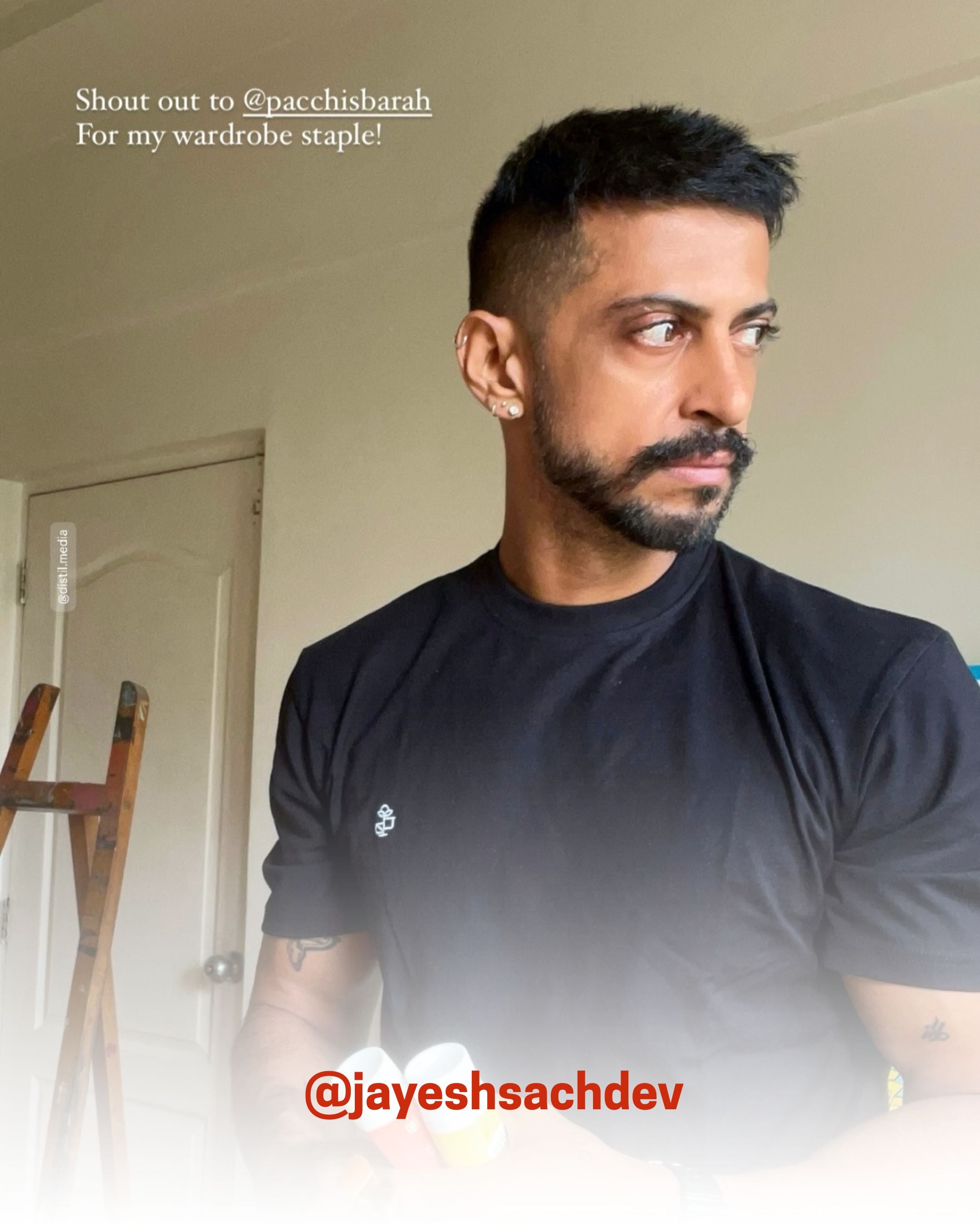 Man indoors wearing a black organic cotton T-Shirt, styled as a wardrobe staple, showcasing 2512’s sustainable t-shirts, a creator favorite eco friendly tee.