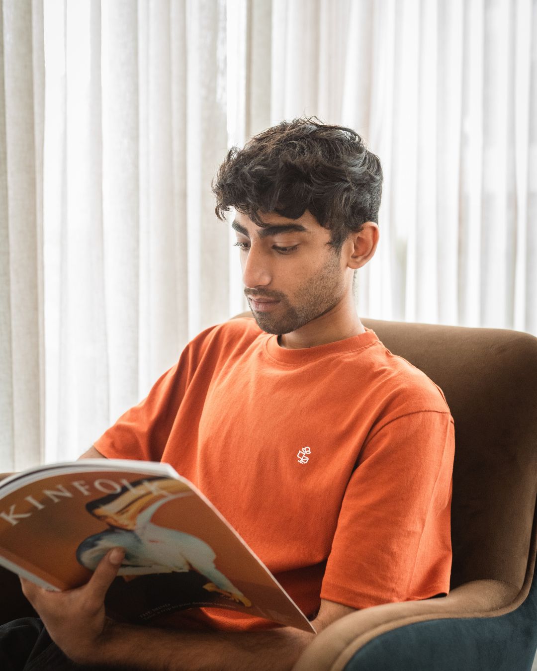man reading magazine wearing rust-colored organic cotton T-shirts from 2512 Pacchis Barah, sustainable t-shirts, eco friendly t-shirts, organic cotton tee, men’s organic cotton t shirts, organic t shirts women