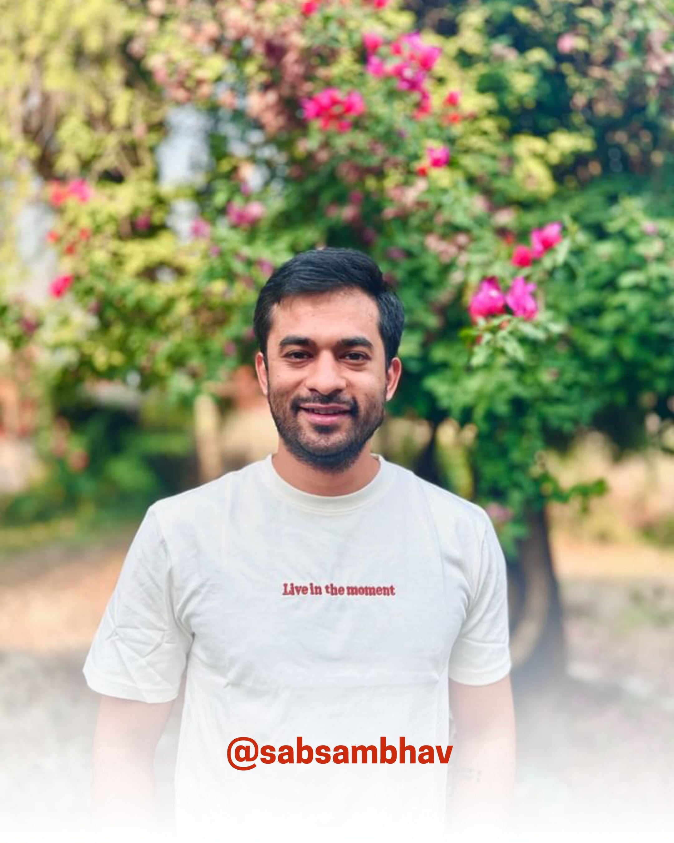 Man smiling outdoors in a white organic cotton T-Shirt with floral background, showcasing 2512’s sustainable t-shirts, a customer favorite eco friendly tee.