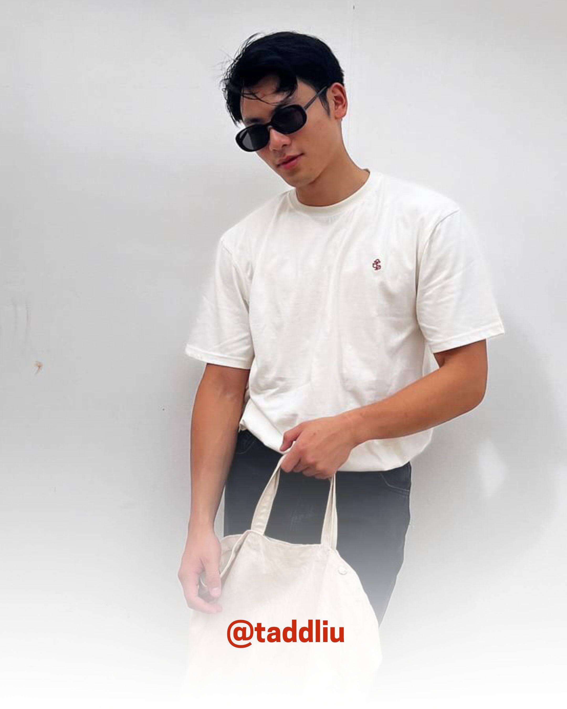 Man in sunglasses wearing a white organic cotton T-Shirt holding a tote bag, showcasing 2512’s sustainable t-shirts, a creator favorite eco friendly tee.