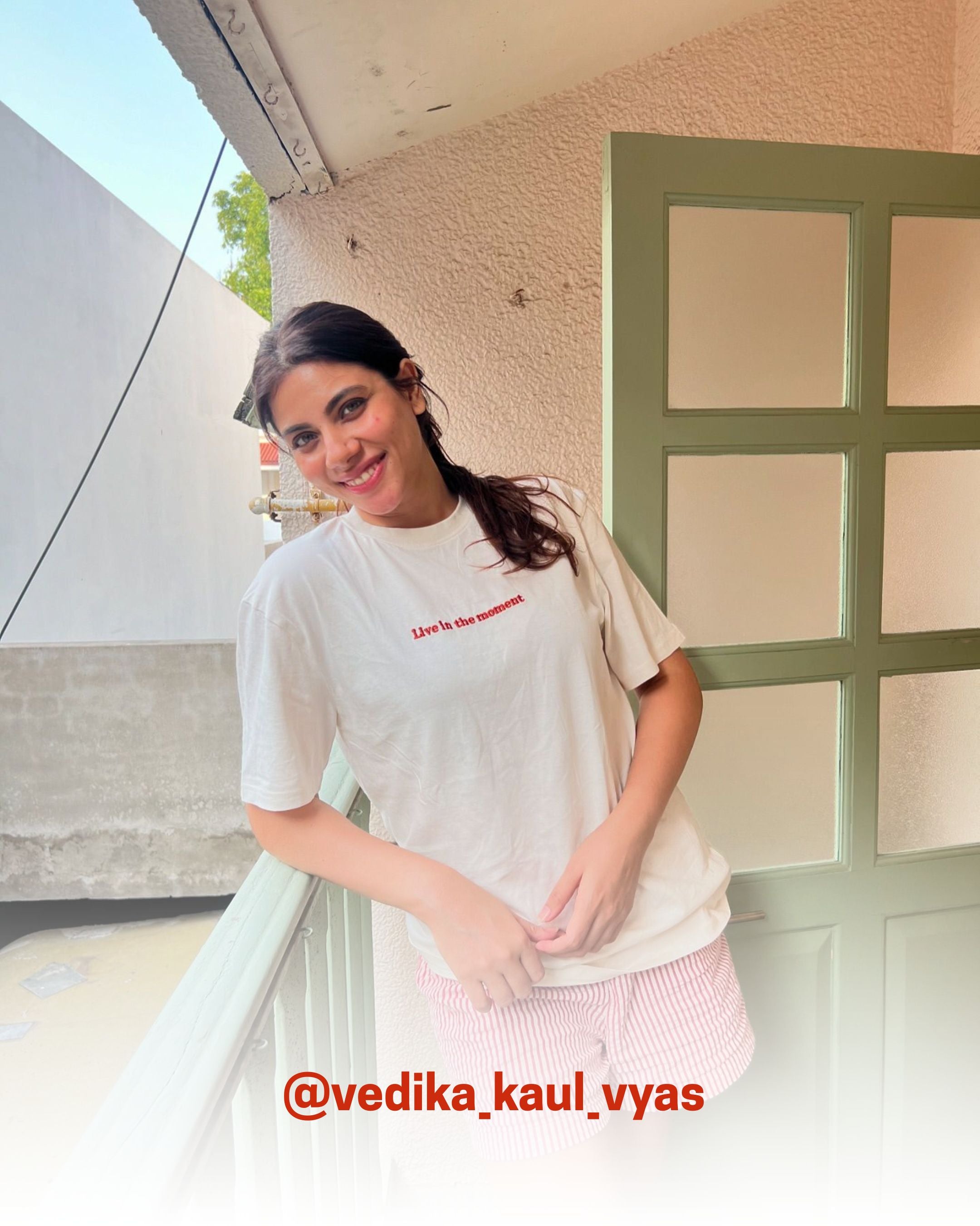 Smiling woman wearing a white organic cotton T-Shirt on balcony, showcasing 2512’s sustainable t-shirts, a creator favorite eco friendly tee.
