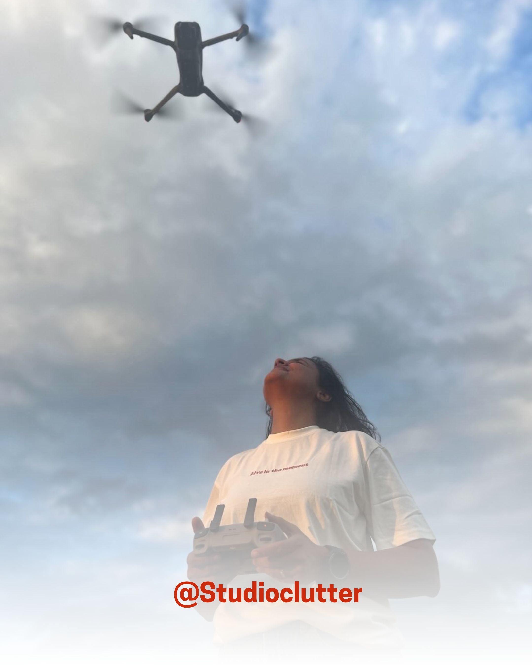 Woman flying a drone under cloudy sky while wearing a white organic cotton T-Shirt, showcasing 2512’s sustainable t-shirts, a creator favorite eco friendly tee.