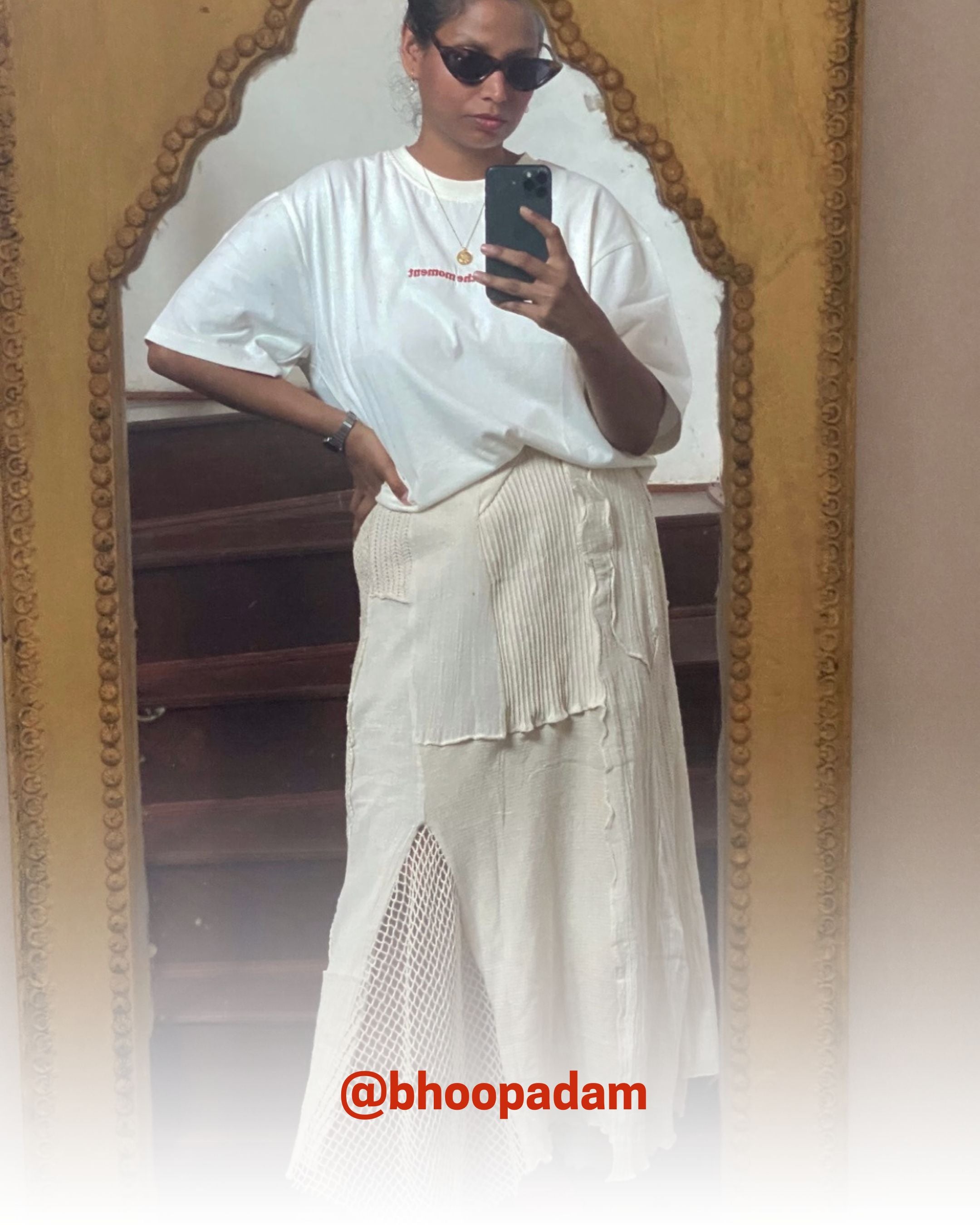 Stylish woman in sunglasses taking a mirror selfie wearing a white organic cotton T-Shirt and skirt, showcasing 2512’s sustainable t-shirts and eco friendly fashion.
