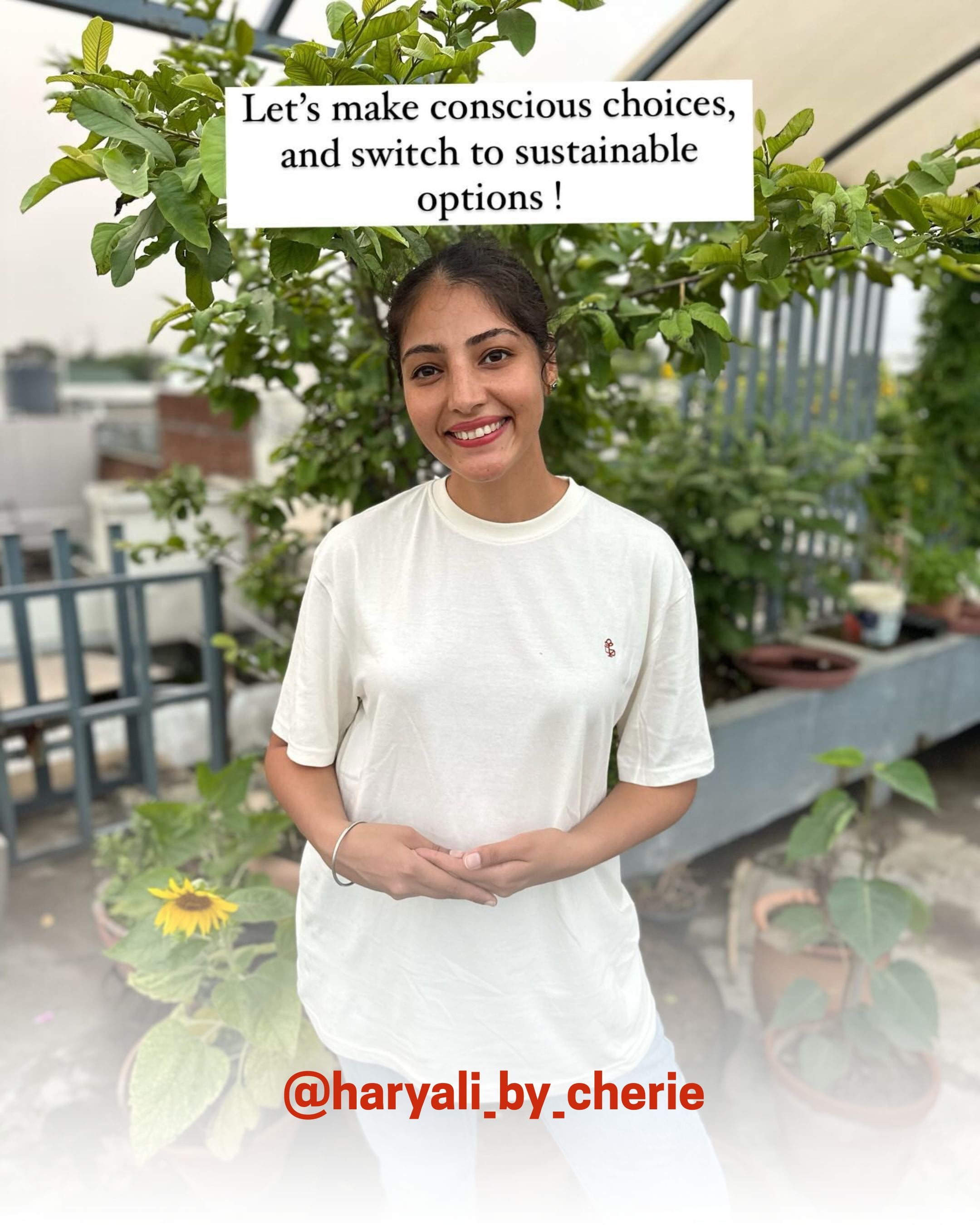 Smiling woman in a white organic cotton T-Shirt from 2512, standing outdoors near plants, showcasing sustainable t-shirts and eco friendly fashion.
