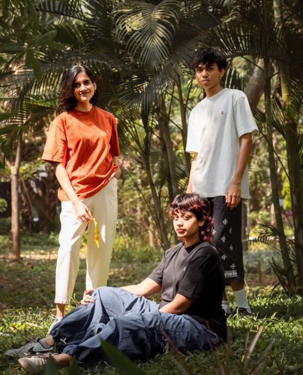 Group of young people wearing 2512 Pacchis Barah organic cotton t-shirts in rust orange, white, and black, showcasing sustainable t-shirts and eco friendly fashion made for men and women.