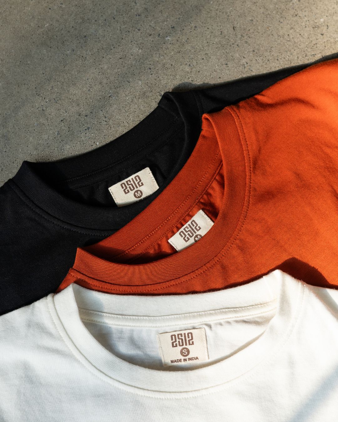 2512 Pacchis Barah sustainable t-shirts made with organic cotton – eco friendly tees in black, rust orange, and white, showcasing timeless capsule wardrobe essentials for men and women.