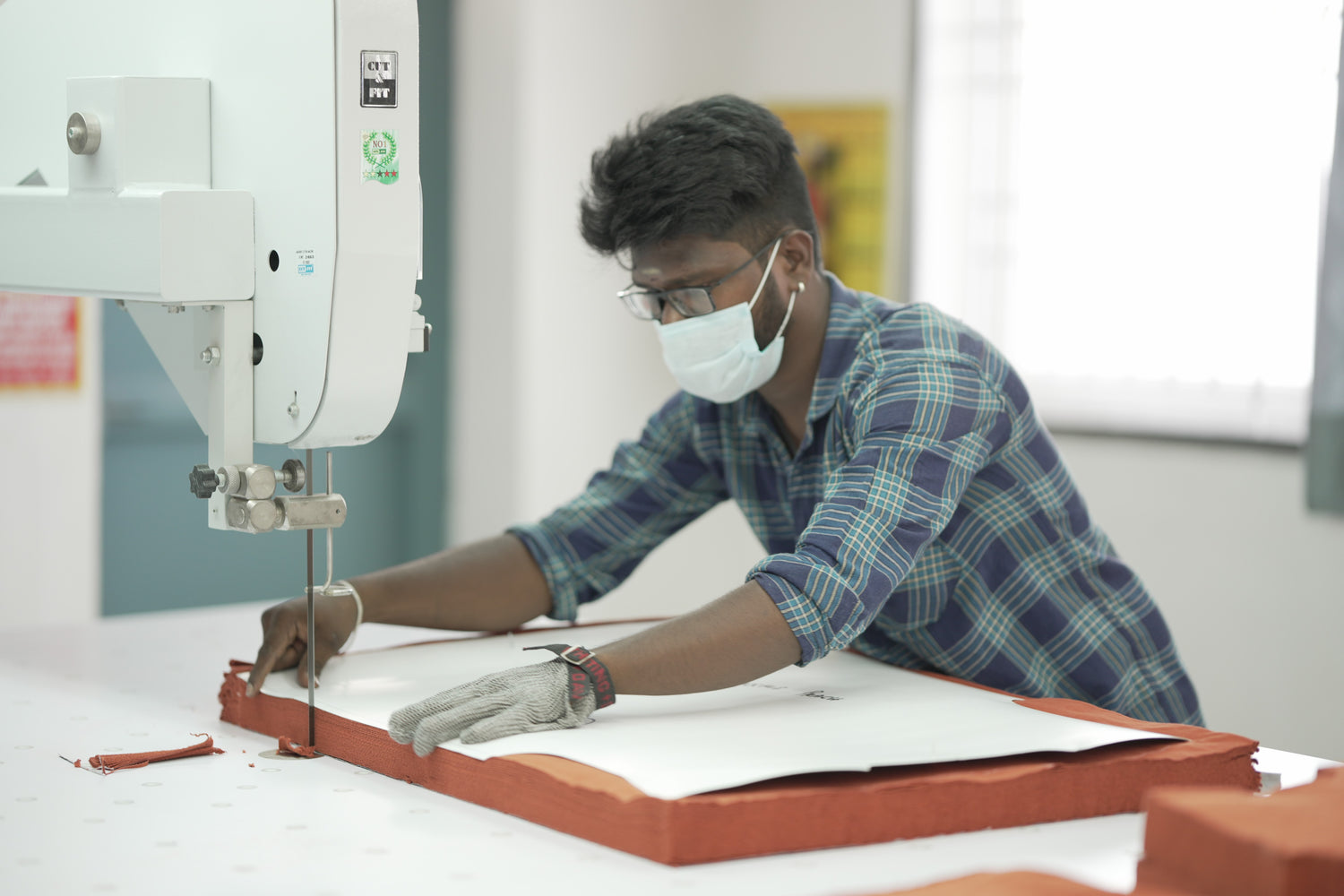 Worker cutting fabric in ethical production unit of 2512 Pacchis Barah, showcasing how sustainable t-shirts and organic cotton t-shirts are carefully crafted with eco friendly practices for unisex wear.