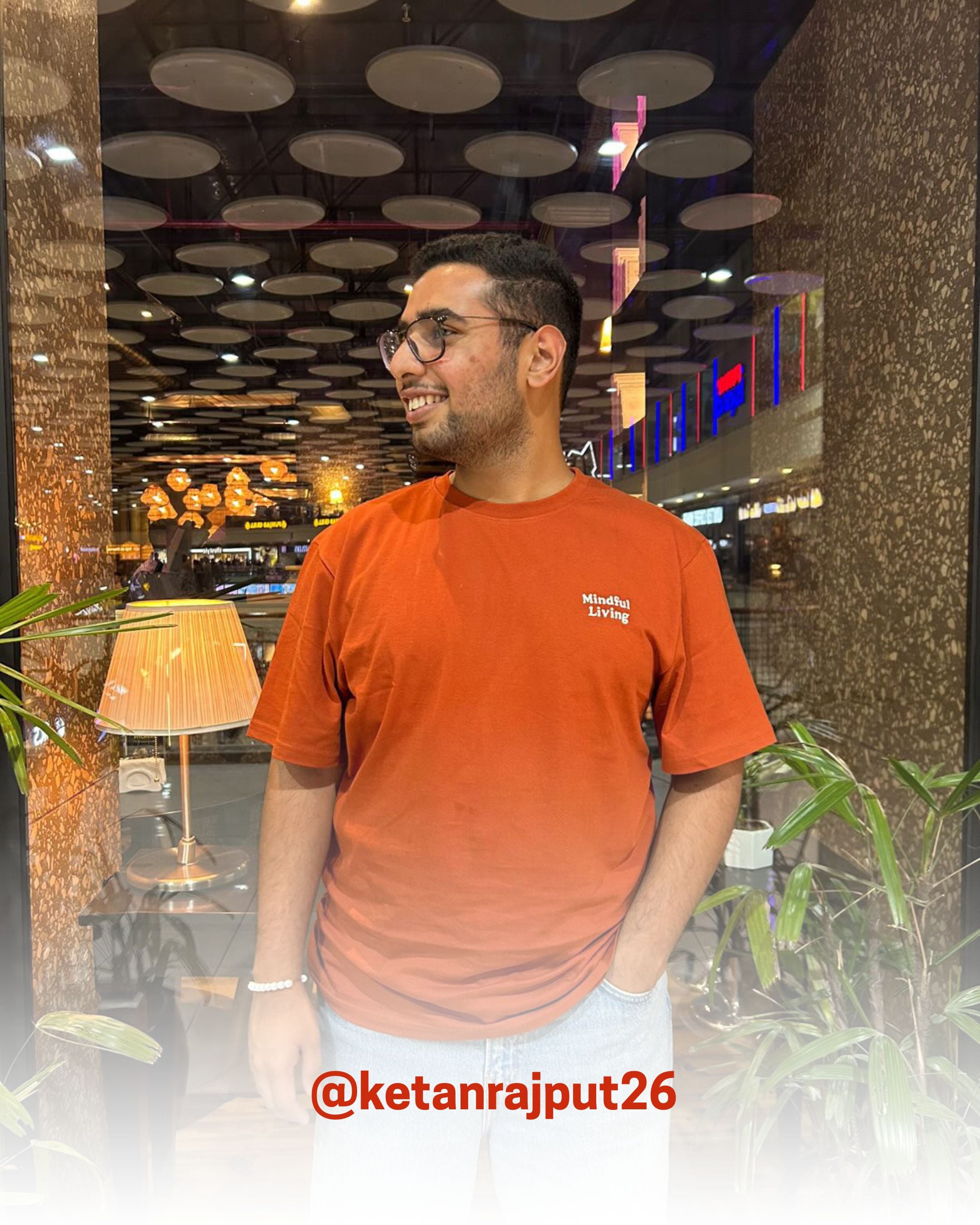 Smiling man wearing a rust organic cotton T-Shirt indoors, showcasing 2512’s sustainable t-shirts, a customer favorite eco friendly tee.