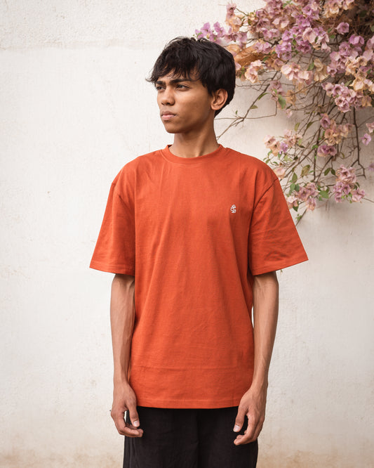 Model wearing rust organic cotton t-shirt with 2512 chest motif, front view