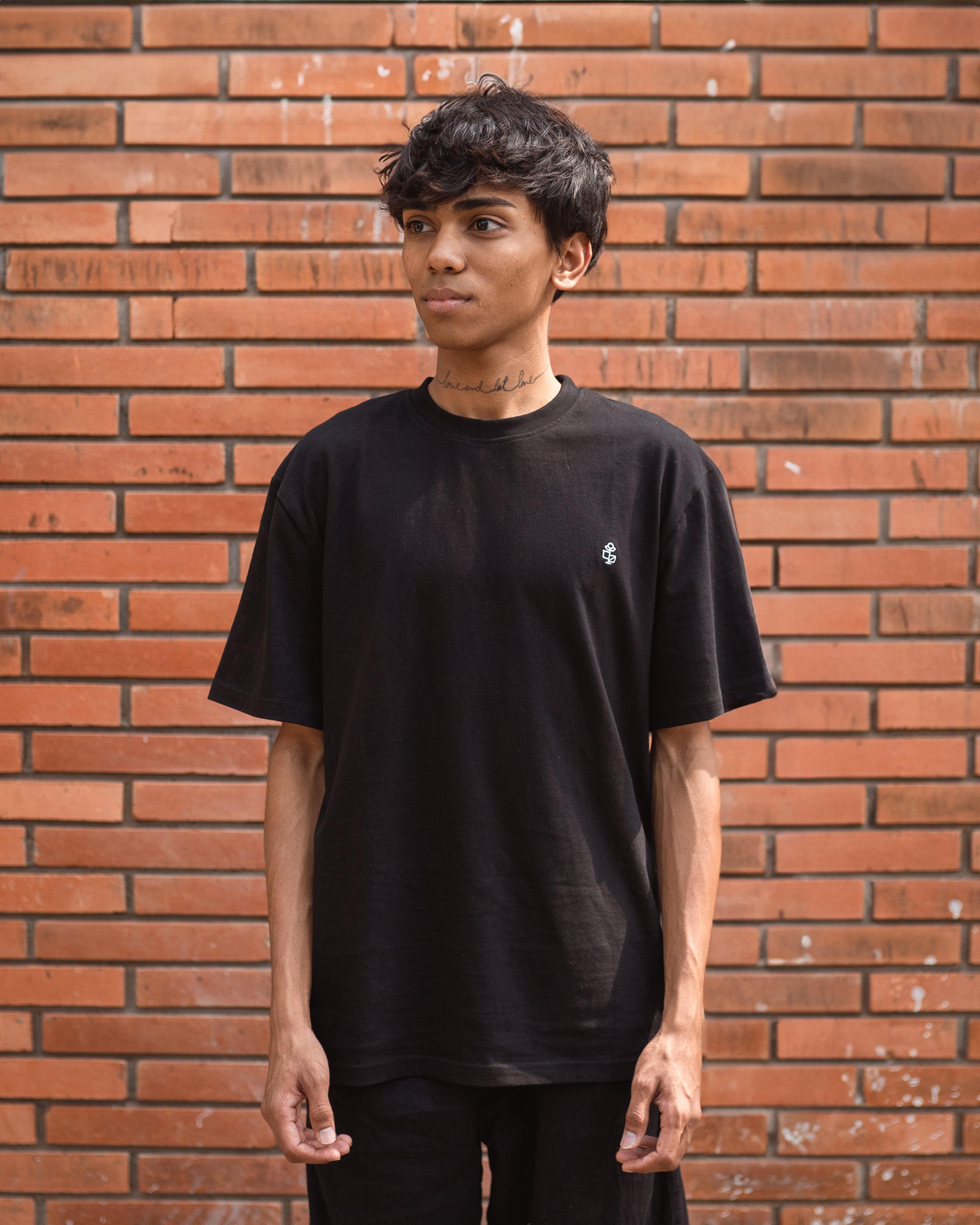 Model wearing black organic cotton unisex t-shirt with 2512 motif, front view.
