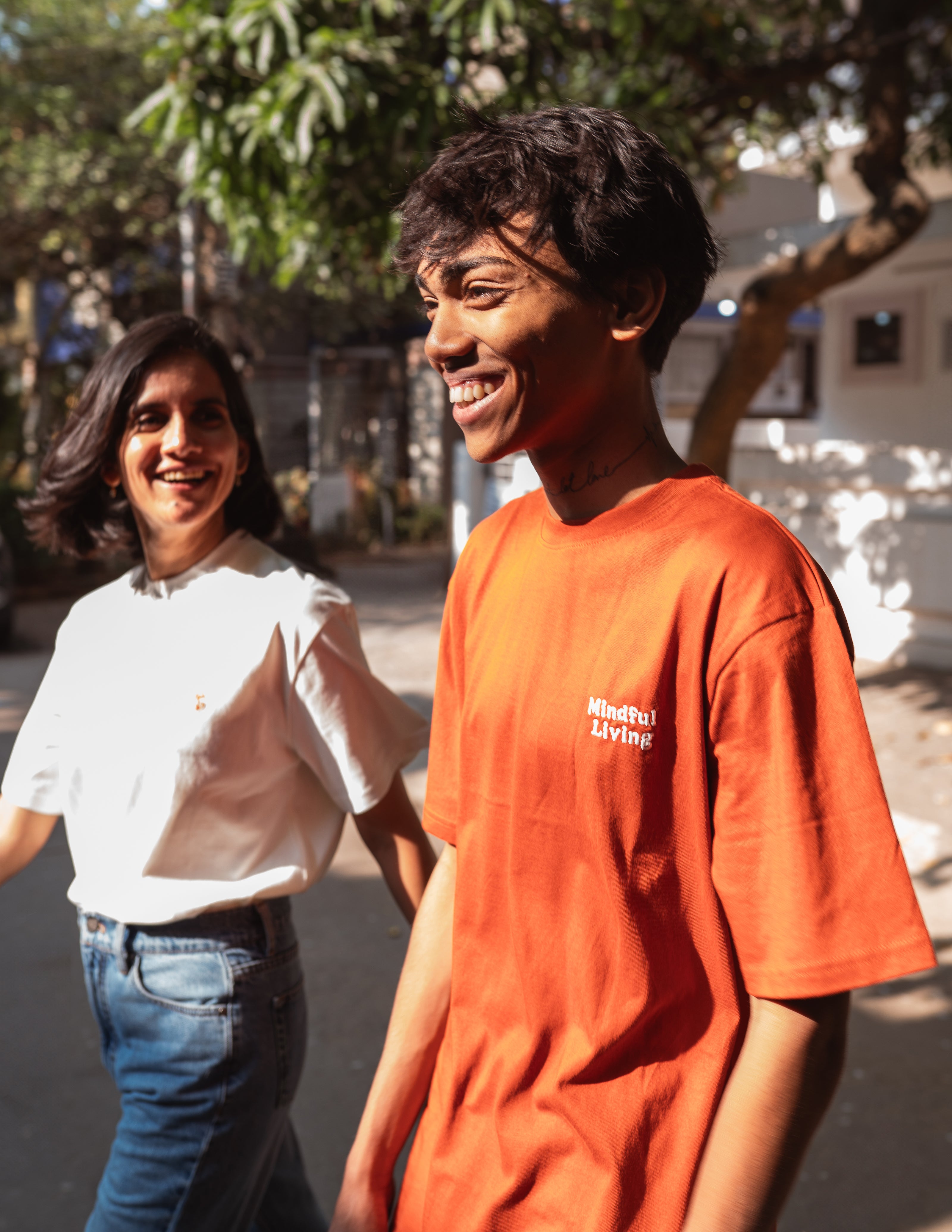Model wearing rust organic cotton unisex t-shirt with 'Mindful Living' embroidery, front view