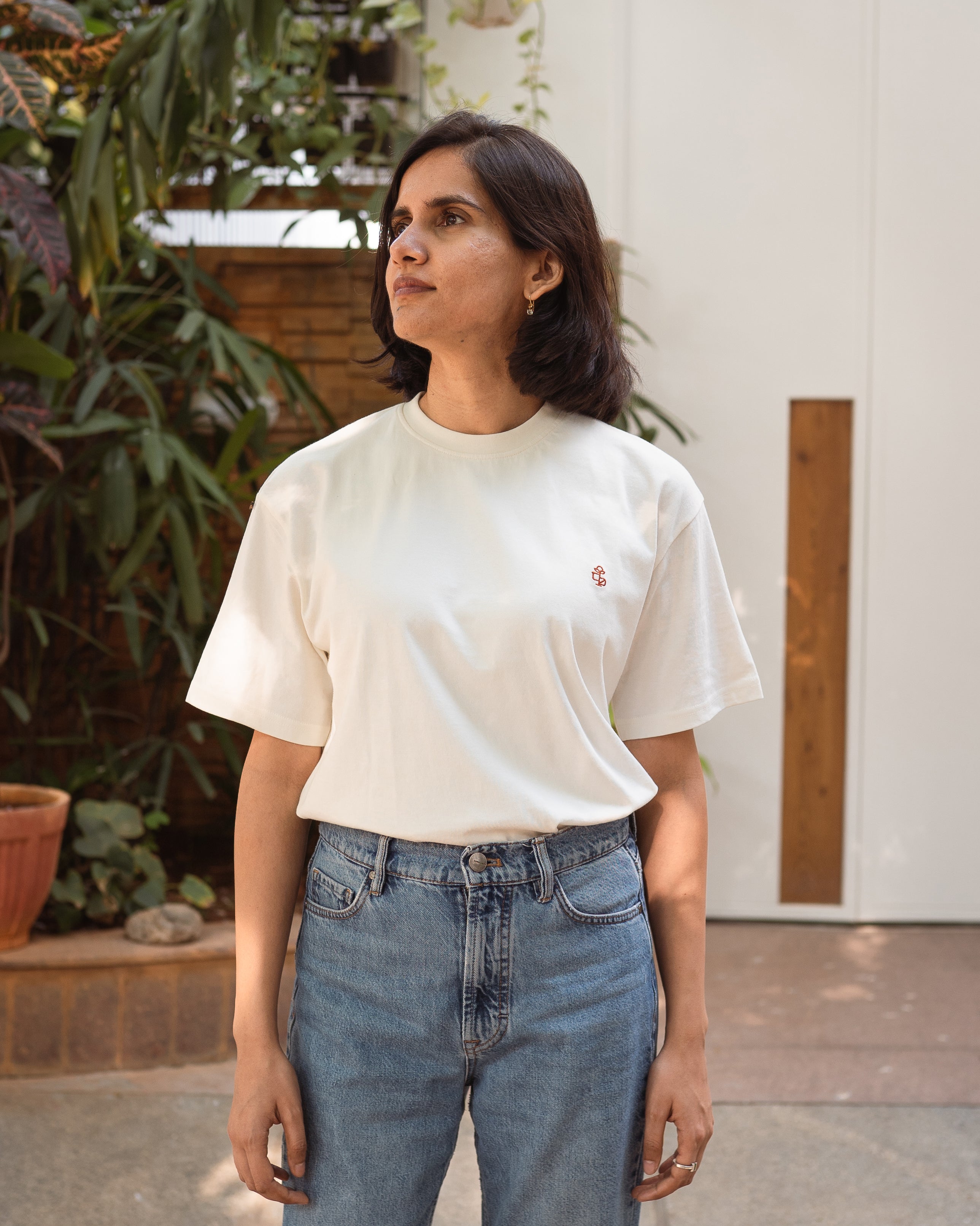 Model wearing white organic cotton unisex t-shirt with tonal 2512 motif, front view