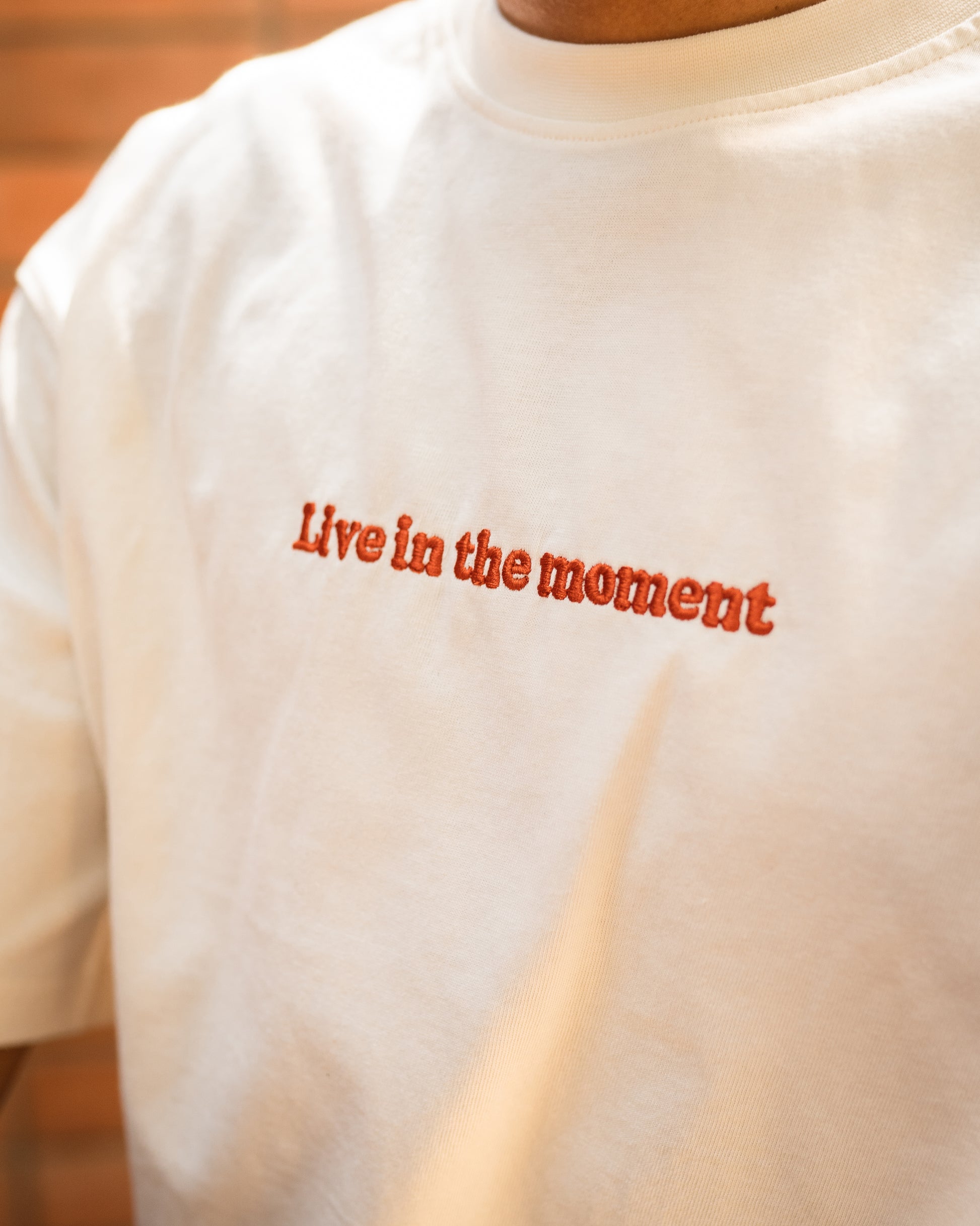 Close-up of 'Live in the Moment' embroidery on soft white cotton